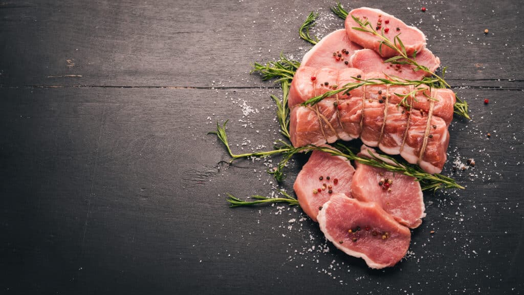 Raw meat Beef fillet with rosemary and spices on a black wooden background. Top view. Free space for text biefstukken